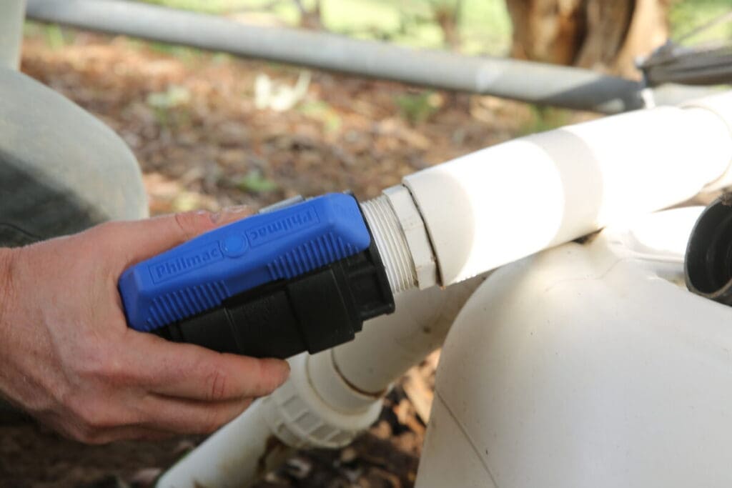 Installer tightening a Philmac valve onto a pipe for a secure water control connection