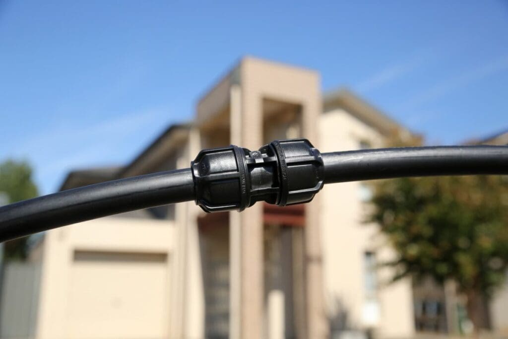 Philmac compression coupling being installed on a poly pipe during a field connection.