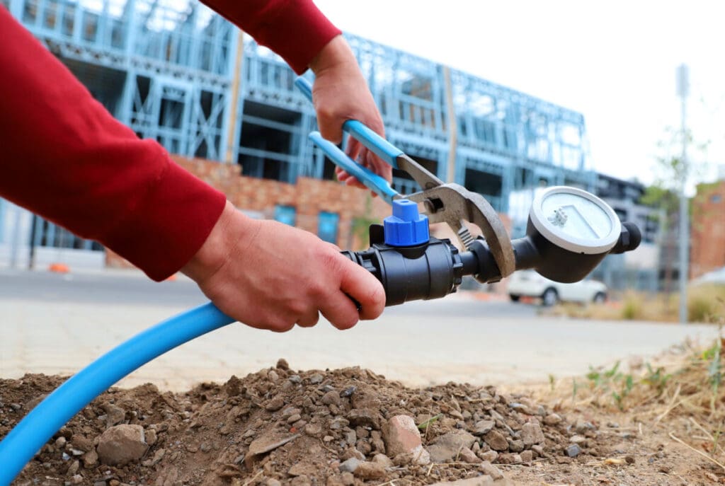 Philmac waterworks fitting connected to underground pipework in a construction environment.