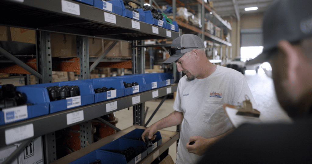 A worker in a warehouse selects Philmac fittings from organised storage bins, representing the reliable solutions trusted by professionals across America.